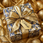 Luxury gift box wrapped in blue and gold geometric paper with a metallic bow and "Celebrate" tag by Wrapped Studios.