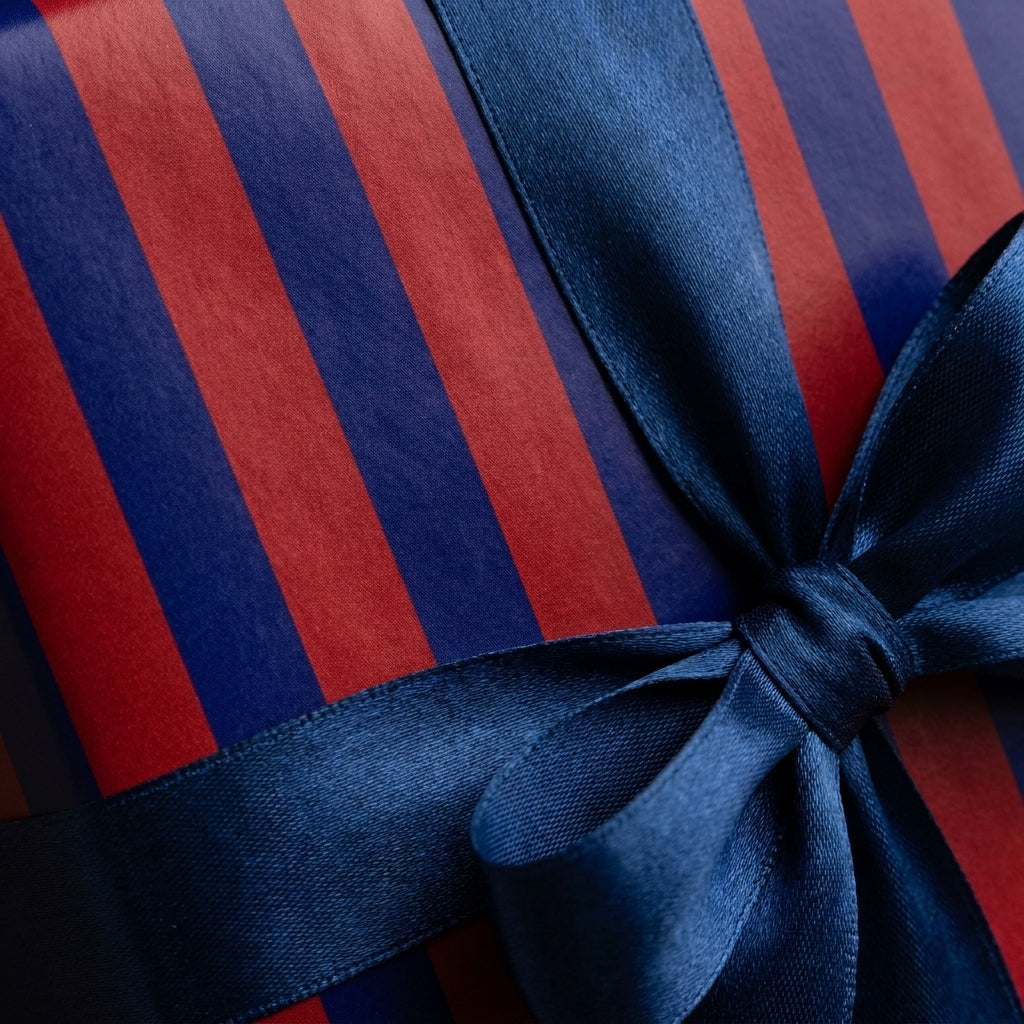 Luxury red and navy striped wrapping paper with a blue satin ribbon bow by Wrapped Studios.