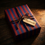 Red and navy striped wrapping paper with a leather bow on a rustic gift box, Wrapped Studios.