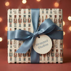 Square gift wrapped in nutcracker Christmas gift wrap with blue satin ribbon and "Wrapped Studios" tag.