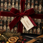 Luxury nutcracker Christmas wrapping paper with a red velvet bow and holiday tag by Wrapped Studios.