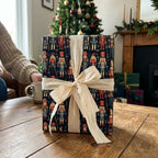 Nutcracker Christmas wrapping paper with cream ribbon by Wrapped Studios on a cozy holiday table.