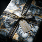 Luxury blue and gold marble wrapping paper by Wrapped Studios, tied with a black ribbon and gold string bow.