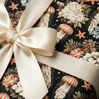 Luxury gift wrap with jellyfish and vintage floral pattern, tied with cream satin bow by Wrapped Studios.