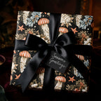 Luxury coastal Christmas wrapping paper with jellyfish pattern and black satin bow by Wrapped Studios.