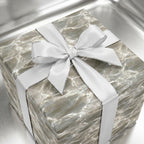 Luxury silver marble wrapping paper with a white satin bow on a gift box, by Wrapped Studios.