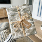 Neutral ocean water luxury wrapping paper with raffia ribbon and gift tag by Wrapped Studios.