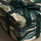 Elegant gift wrapped in modern abstract green wrapping paper with a dark green velvet ribbon and bow.