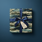Gift wrapped in wave-patterned paper with a navy ribbon and "A Wave of Gratitude" tag, set against a matching navy background.