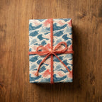 Japanese ocean wave wrapping paper with a coral twine bow on a wood table by Wrapped Studios.