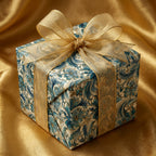 Decorative gift box with floral paisley pattern and gold ribbon on a satin background