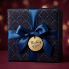 Elegant gift with dark floral wrapping paper, tied with a blue ribbon and "Thinking of You" tag.