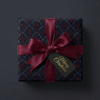 Elegant Christmas gift wrapped in damask floral paper with a burgundy satin ribbon and "Merry Christmas" tag.