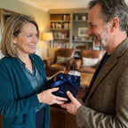 Woman receiving a dark floral gift wrap with a navy bow, perfect for elegant gifting.