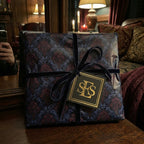 Elegant gift wrapped in dark floral wrapping paper with a velvet navy ribbon and monogram tag.