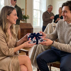 Man giving a gift in elegant blue floral wrapping paper with a navy velvet bow, by Wrapped Studios.