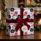 Elegant floral Christmas wrapping paper with a red velvet bow on a gift box, by Wrapped Studios.