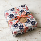 Luxury floral wrapping paper with navy and pink flowers, coral ribbon, and gift tag by Wrapped Studios.