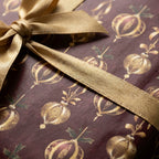 Luxury Christmas wrapping paper in burgundy and gold with ornament pattern and ribbon by Wrapped Studios.