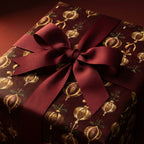 Luxury Christmas gift wrap with gold ornament pattern and burgundy ribbon by Wrapped Studios.