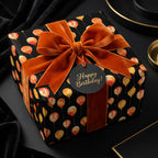 Luxury birthday wrapping paper with orange balloons and velvet ribbon on a black gift box by Wrapped Studios.