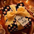 Balloon birthday wrapping paper with a gold ribbon and 'Make a wish' tag by Wrapped Studios.