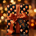 Luxury birthday wrapping paper with orange balloons on black, with copper ribbon by Wrapped Studios.