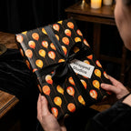 Elegant black birthday wrapping paper with watercolor balloons and a satin bow, by Wrapped Studios.