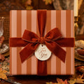 Luxury autumn striped wrapping paper with a rust velvet ribbon and gift tag by Wrapped Studios.