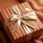 Terracotta striped luxury gift wrap with cream satin ribbon and 'With Love' tag by Wrapped Studios.