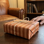Rustic brown striped wrapping paper with a twine bow on a gift box, by Wrapped Studios.