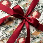 Elegant watercolor Christmas wrapping paper with red ornaments and satin bow by Wrapped Studios.