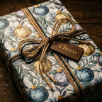 Elegant Christmas wrapping paper with watercolor ornaments, twine bow, and Cheers tag by Wrapped Studios.