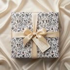 Elegant floral wrapping paper with a gold ribbon on a square gift box, perfect for birthdays or special occasions.