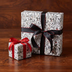 Elegant gifts wrapped in floral wrapping paper, tied with black and red satin ribbons.