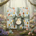 Square gift in light blue wrapping paper with tree pattern and sage ribbon, gift tag reads "A Little Something".
