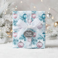 Elegant Christmas gift wrap featuring ornament pattern, white ribbon, and "Happy Holidays" tag.
