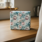 Christmas gift wrapped in blue paper with ornament and pine branch pattern; tied with white string.