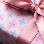 Pastel pink and blue birthday wrapping paper with a satin ribbon bow by Wrapped Studios.