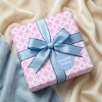 Pastel pink and blue geometric baby shower wrapping paper with a satin bow, by Wrapped Studios.