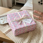 Pastel pink and blue birthday wrapping paper with a white ribbon bow by Wrapped Studios.