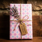 Pastel baptism wrapping paper by Wrapped Studios with a cross pattern, tied with rustic twine and lavender.