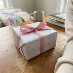 Pastel vintage floral wrapping paper with a pink ribbon on a gift box. Wrapped Studios.