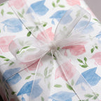 Watercolor graduation wrapping paper in pastel pink and blue with a sheer white ribbon bow by Wrapped Studios.