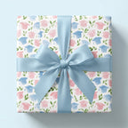 Watercolor graduation wrapping paper with pink and blue caps and a blue bow by Wrapped Studios.