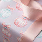 Pastel Christmas wrapping paper with watercolor ornaments and pink satin ribbon by Wrapped Studios.
