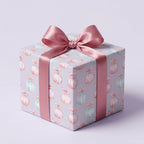 Pastel Christmas wrapping paper with watercolor ornaments and a pink satin bow by Wrapped Studios.