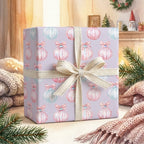 Pastel Christmas wrapping paper with watercolor ornament pattern and cream bow by Wrapped Studios.