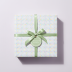 Square gift box in pastel polka dot wrapping paper with a sage green ribbon.