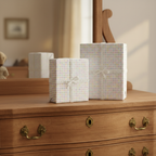 Two gifts wrapped in polka dot baby shower wrapping paper with lace ribbons sit on a wooden dresser.
